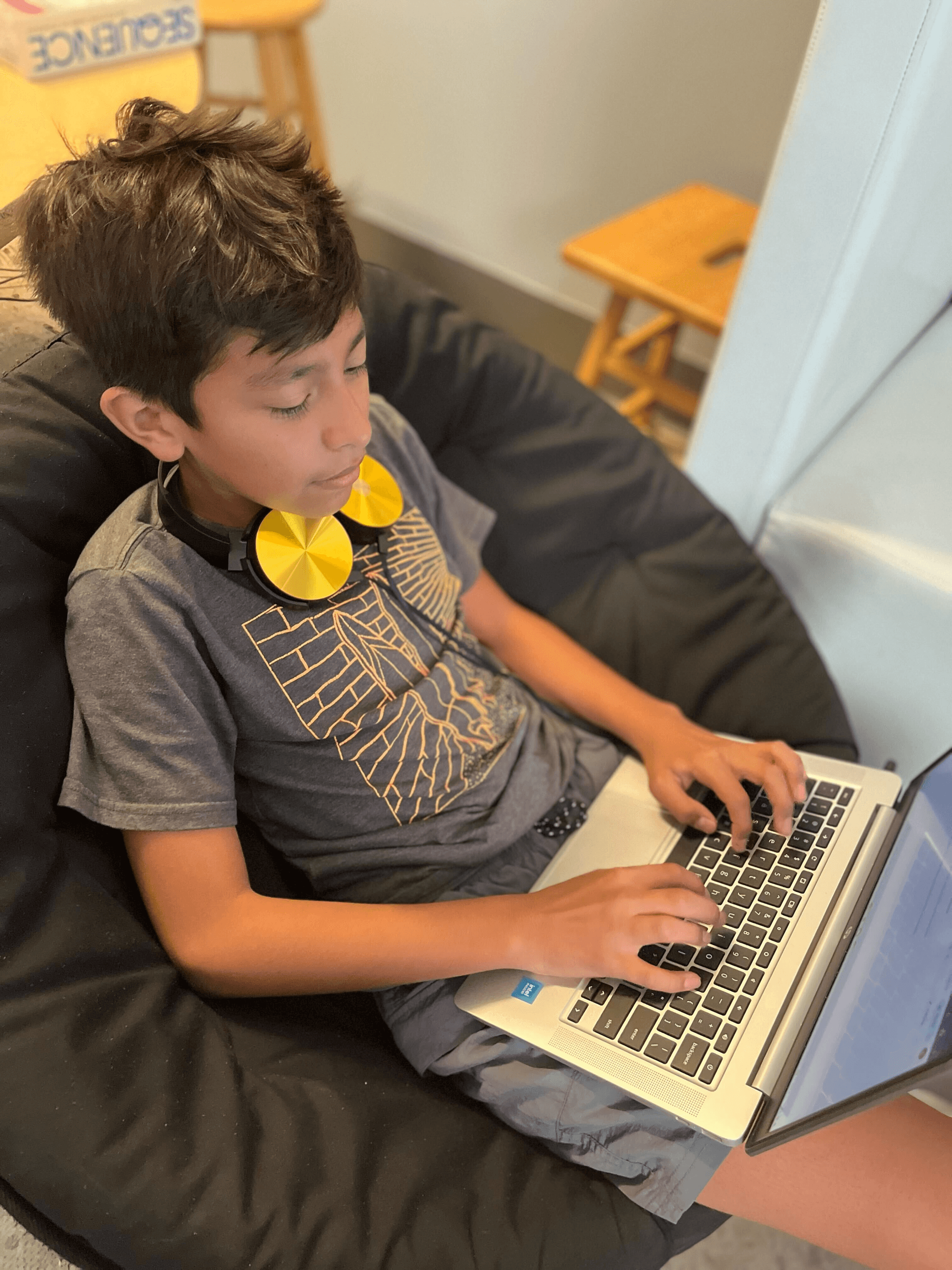 Student engaged in learning with laptop and headphones in a modern classroom setting